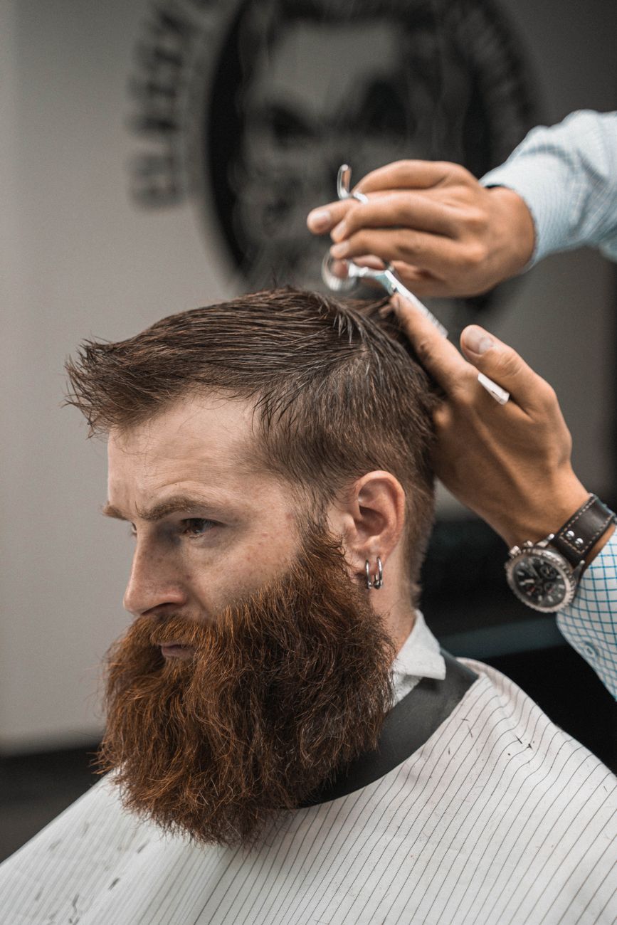 A barber finishing a customer's haircut